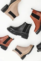 Botas tipo chelsea de cuero con suela track dentada y paneles elásticos laterales. Presentan costuras a contratono y tirador en la parte trasera.
