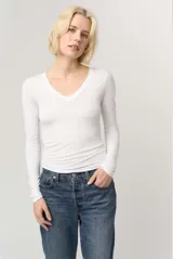 Remera de manga larga blanca, confeccionada en jersey liviano de tacto suave, con escote en V limpio y calce que acompaña el cuerpo.