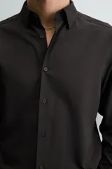 Camisa de corte slim fit, color negro, con cuello italiano, manga larga con puños abotonados y cierre frontal de botones. Confeccionada en tejido de fácil cuidado que minimiza la necesidad de planchado.