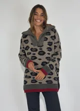 Sweater de tejido de punto con estampado animal print de leopardo en tonos beige y negro. Presenta cuello polo con cierre parcial, puños y ruedo en tejido acanalado gris oscuro con una línea de contraste color bordó.