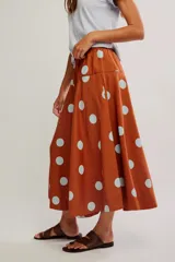 Falda midi de corte A y cintura baja, confeccionada en popelina de algodón color marrón terracota con estampado de lunares celestes.