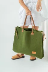 Bolso grande de fieltro color verde oliva con asas de cuero marrón.