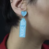 Aros colgantes con forma rectangular con glitter y la leyenda "Make Up" en uno y "Lover" en el otro.