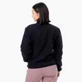 Campera polar sherpa de mujer en color negro, con cuello alto, cierre de botones a presión, bolsillos frontales con refuerzo en nylon y parche con logo de la marca en el pecho.