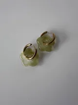 Aros de acero quirúrgico con argollas doradas y dije colgante en forma de flor color celeste.