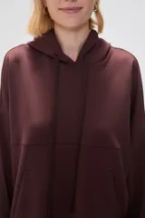 Canguro negro holgado con capucha y cordones ajustables, mangas largas y bolsillos laterales.