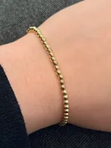 Pulsera elástica de baño en oro con cuentas esféricas pequeñas.