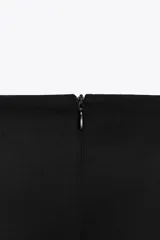 Falda pantalón negra de tiro alto con diseño cruzado y pliegues drapeados en el frente.