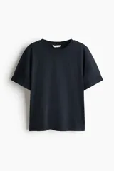 Remera de algodón de color negro, corte holgado con hombros caídos, cuello redondo acanalado y mangas cortas con doblez cosido.