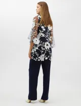 Conjunto de tres piezas compuesto por una musculosa de silueta recta, un pantalón de seda fría con caída fluida y cintura elastizada, y un kimono de tul con bordado floral, frente abierto y mangas acampanadas. Incluye collar largo removible.