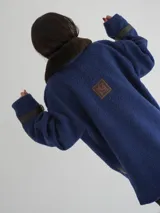 Buzo color crudo con cuello de piel sintética color crema, abertura parcial con cierre de cuero marrón y hebilla dorada, puños con ajuste de cuero marrón y bolsillos laterales.