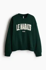 Buzo de cuello redondo con hombros caídos y diseño estampado frontal con la inscripción Le Marais Paris. Presenta puños y bajo acanalados.