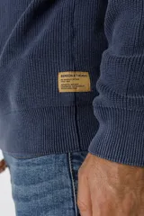 Sweater de punto en color azul marino, con cuello redondo y mangas raglán. Presenta un tejido acanalado fino y puños elásticos.