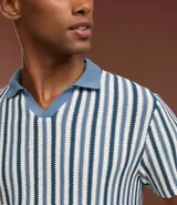 Polo de punto de manga corta para hombre, con cuello estilo cubano (sin botones) y patrón de rayas verticales en tonos azul marino, blanco y gris claro.