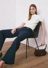 Pantalón azul marino de tiro medio y corte flare, con bolsillos frontales decorados con botones dorados.