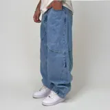 Pantalón de jean estilo ultra baggy con diseño de paneles curvos en las piernas. Presenta un lavado claro, bolsillos traseros amplios y costuras reforzadas que definen su silueta holgada y voluminosa.