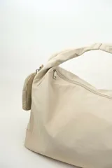 Bolso tipo shopper de nylon color beige, con cierre superior y correa de hombro integrada. Incluye un pequeño monedero colgante lateral.