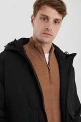 Campera impermeable negra con capucha, cierres a tono y cursores negros metalizados, bolsillos frontales con tapa, elásticos regulables en el ruedo e interior térmico con detalles confeccionados con láser.