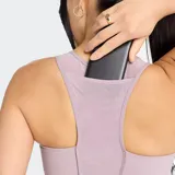 Top deportivo de soporte medio, color lila claro, con escote redondo y tirantes anchos. Presenta un bolsillo trasero para teléfono y banda elástica de apoyo inferior.
