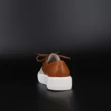 Zapatillas acordonadas tipo championes, confeccionadas en cuero color suela y blanco, con base de goma blanca.