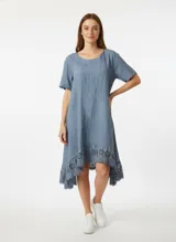 Vestido a la rodilla color celeste, de corte amplio, cuello redondo y mangas cortas. Presenta detalle de broderie en el ruedo.