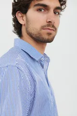 Camisa celeste con rayas verticales blancas, de manga larga con puños abotonados y cuello clásico.