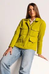 Chaqueta color verde lima de tejido en lana, con cuello clásico, cierre frontal con botones dorados y cuatro bolsillos con solapa en el frente.
