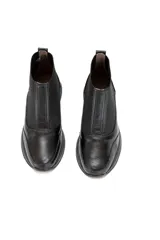 Botín tipo Chelsea de caña baja, color negro, confeccionado en cuero vacuno liso con inserciones de tejido elástico en los laterales y detalle texturizado efecto escama en el talón. Cuenta con plataforma ligera y plantilla de látex para mayor confort.