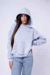 Canguro con capucha color blanco, confeccionado en algodón, con bolsillo frontal tipo canguro y pequeño bordado en el pecho.