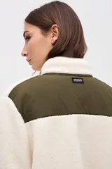 Campera de sherpa doble faz en color crema con detalles en verde oliva. Presenta cierre frontal con botones, bolsillos laterales de nylon capitoneado y terminaciones en contratono. Diseño de calce relajado con bordado en la manga.