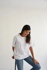 Remera color crema de manga corta con estampado en la espalda que incluye una ilustración y la frase "Big Waves Club" en color lila.