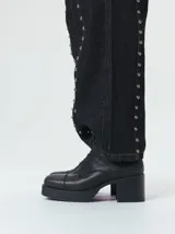 Bota de cuero tipo borceguí con cordones, cierre lateral metálico y taco cuadrado alto con plataforma. Presenta punta cuadrada y diseño robusto.