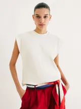 Musculosa de punto color beige, con cuello redondo y hombreras marcadas que le dan una estructura definida.