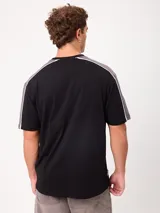 Remera negra de manga corta con diseño deportivo, parte superior de las mangas en color gris con ribete blanco y estampa frontal con la marca Rusty.