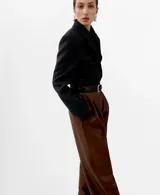 Pantalón de corte wide leg, confeccionado en material sintético efecto cuero color marrón, con pinzas en la cintura y bolsillos laterales.