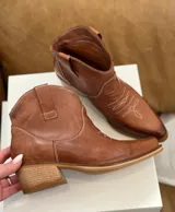 Bota corta texana color marrón de cuero, con forro de cuero, taco bajo y punta cuadrada.