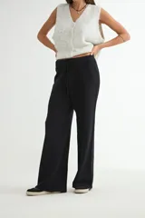 Pantalón de tejido de punto color negro, de corte recto y holgado, con cintura elástica y cordón ajustable.