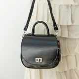 Cartera bandolera de cuero color marrón con asa corta superior y correa larga ajustable.