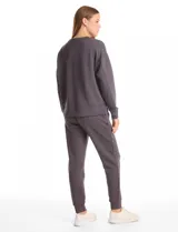 Buzo deportivo de cuello redondo, con hombros caídos y mangas largas con puños. Presenta costuras decorativas tipo pespunte en la parte frontal y en las mangas, con un diseño de ruedo recto y tajos laterales.