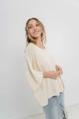 Sweater oversize de tejido liviano color blanco roto, con textura semi traslúcida, escote redondo y mangas amplias estilo murciélago.
