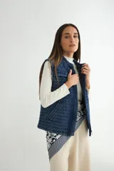 Chaleco de denim acolchado con efecto lavado, diseño sin mangas, cierre frontal y bolsillos laterales.