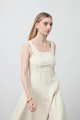 Vestido midi sin mangas de color azul oscuro, con escote cuadrado y silueta evasé. Presenta costuras a contratono en color blanco que recorren verticalmente el diseño, aportando estructura y un detalle gráfico. Confeccionado en tejido con cuerpo y caída firme.