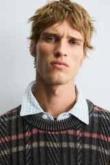 Jersey de punto con ajuste relajado, cuello redondo y manga larga. Presenta un diseño de rayas horizontales multicolores sobre una base oscura con textura de ochos y efecto lavado.