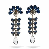 Caravanas largas con diseño colgante, compuestas por una estructura superior en forma de abanico con cristales azules, seguida de una serie de eslabones con forma de lazo también en cristales azules y finalizando con un cristal transparente en forma de gota. Poseen cierre de clip.