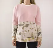 Buzo deportivo unisex color crema con estampado de hojas y manchas de colores.