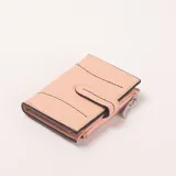 Billetera color rosado con detalles de costuras decorativas en negro y beige. Cuenta con cierre de solapa con botón a presión y un bolsillo exterior con cierre.