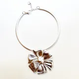 Gargantilla plateada rígida con dije desmontable de flor y cadena para regular el largo.