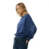 Buzo Rip Curl estilo off shoulder de color azul, con diseño holgado, mangas largas y estampa con el nombre de la marca en la manga.