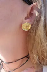 Aros tipo botón dorados con textura irregular que simula la superficie de un molusco.