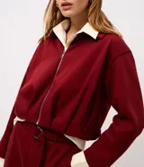 Campera corta en algodón con felpa color bordó, de diseño baloné con cierre frontal metálico y cuello clásico.
